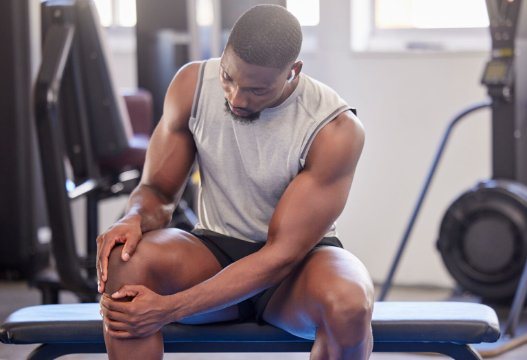 Athlete assessing knee discomfort during a gym session